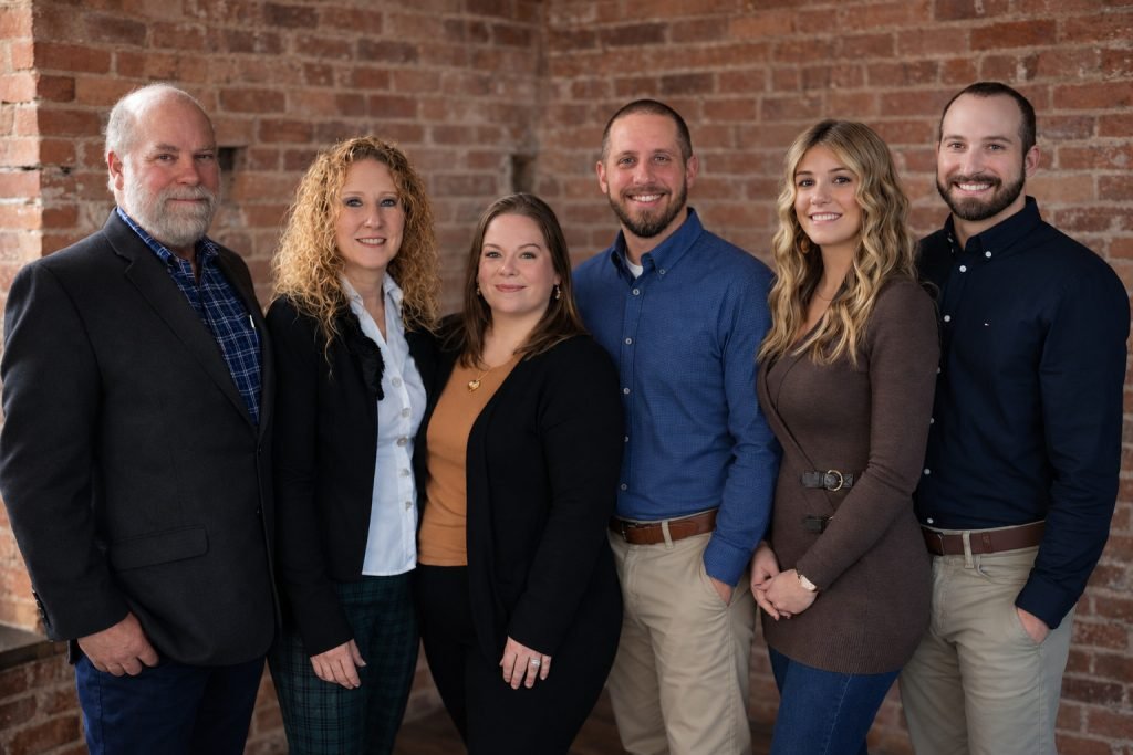 The Veriton Insurance Group team together in front of a natural brick wall.